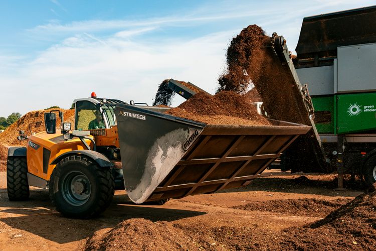 A telehandler tipping bark into a screening machine